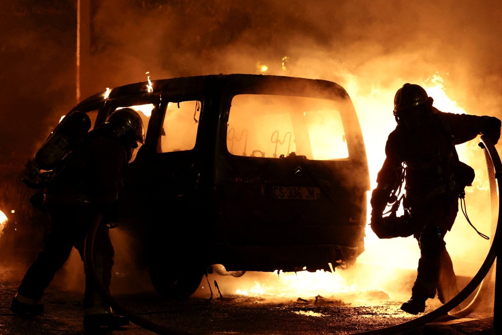 法国消防队员正在扑灭示威者放火烧著的汽车。路透社