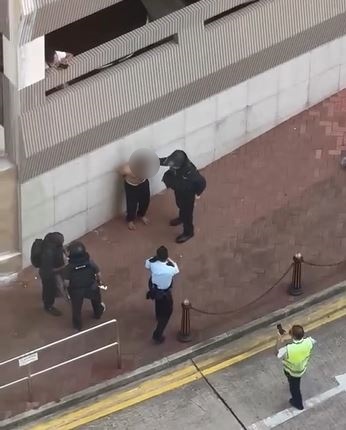 疑兇被反鎖雙手站在路旁。網片截圖