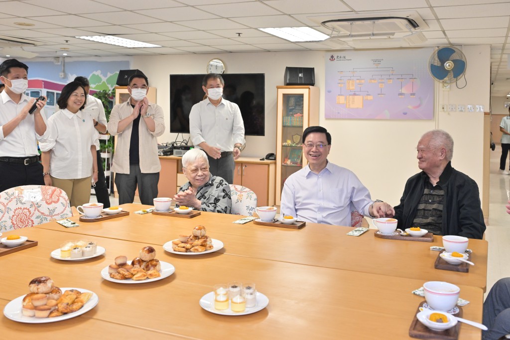 李家超參觀社會服務大樓，期間與一名106歲伯伯（右）談起打麻將心得。政府新聞處