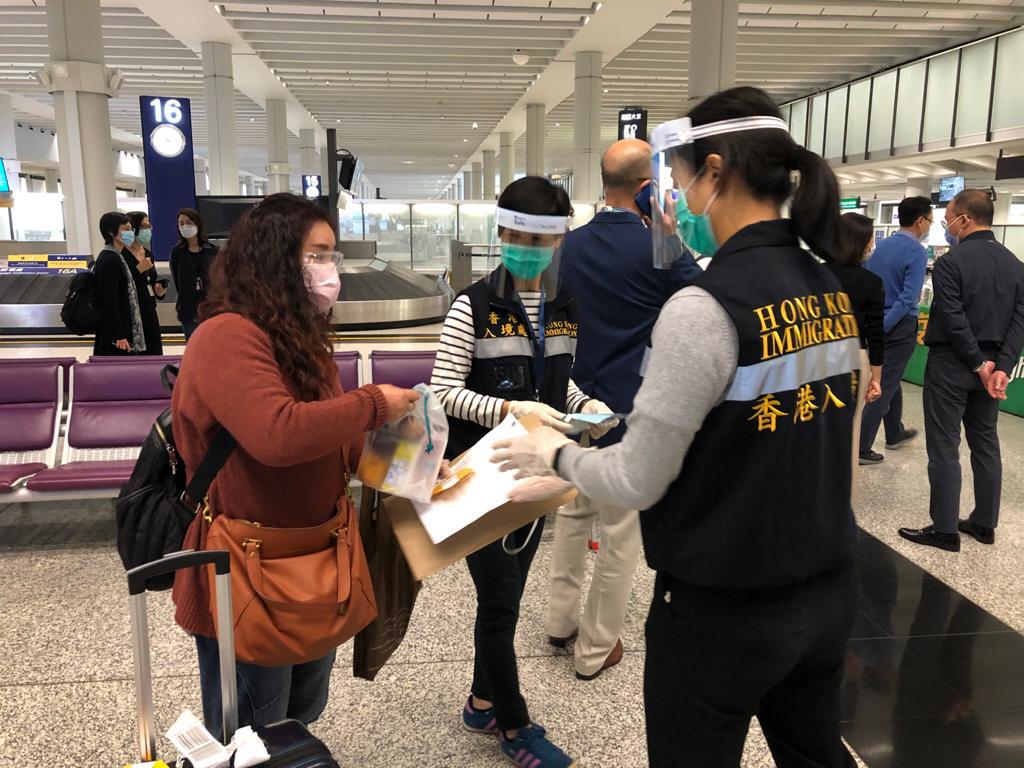 入境處人員在香港機場為乘坐包機的港人送上由航空公司提供的食物包。
