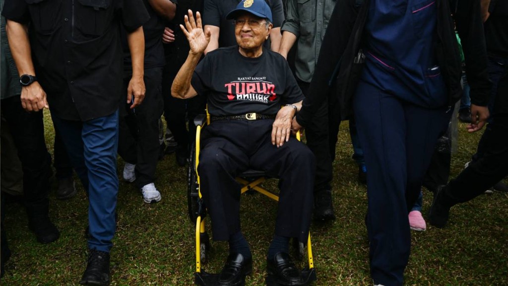 大馬百歲前首相馬哈蒂爾家中摔倒入院。圖為他去年坐輪椅出席群眾活動。法新社