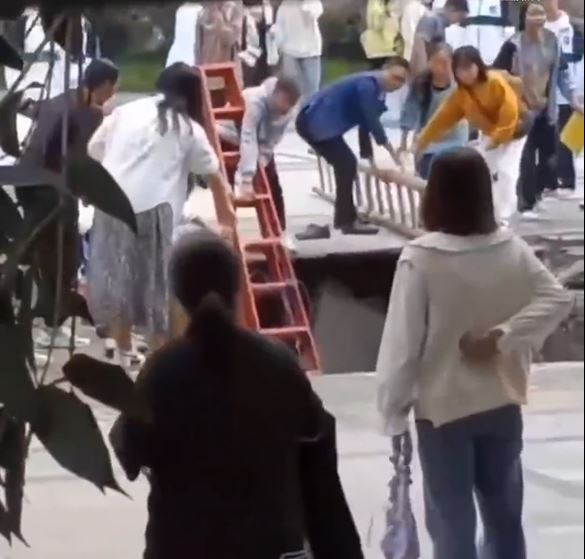 一众教师学生急搬来梯子放入化粪池救人。影片截图