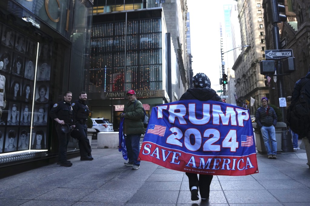 一名妇女在第五大道上行走，举著一面支持前总统特朗普的旗帜。AP