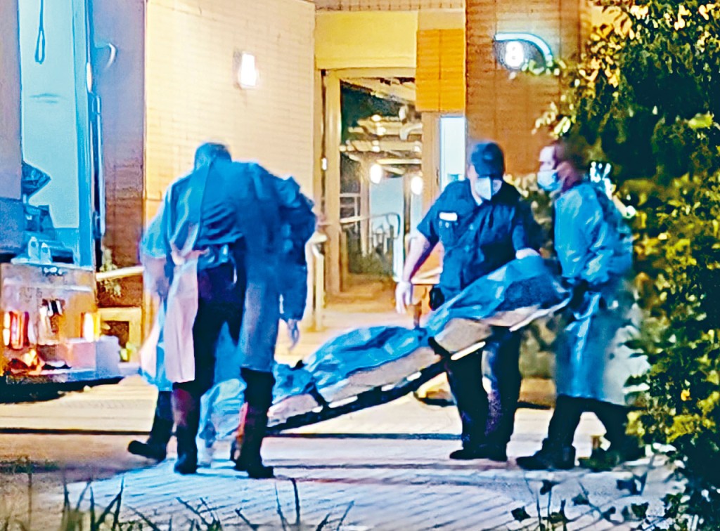 仵工將燒炭身亡男子屍體舁送殮房。