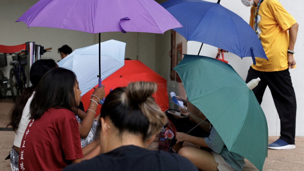 粉絲冒着大太陽撐傘排隊買泰勒絲新加坡演唱會門票。 路透社