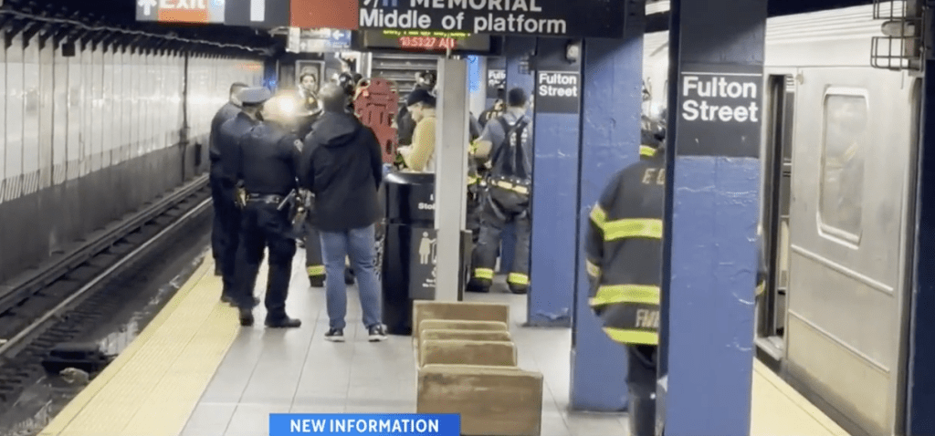 在曼哈顿下城区富尔顿街地铁站内，一名男子将女友推下路轨，令其截肢。新闻画面截图