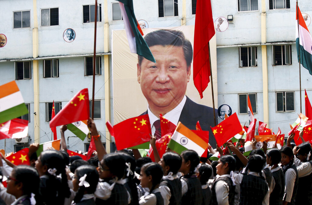 當地民眾揮舞中印國旗，手舉習近平照片。AP