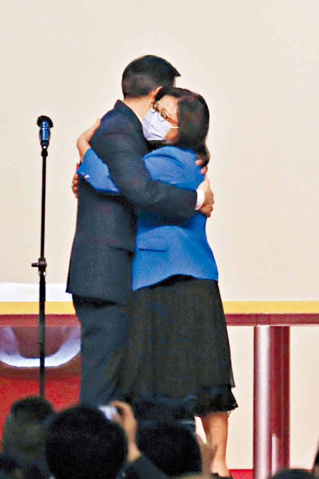 林麗嬋身穿鮮藍色套裝上台，與李家超擁抱。