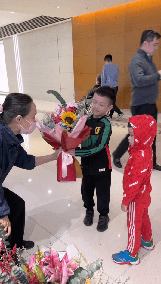 5岁大仔陈裕炘接过花店店员的花束。