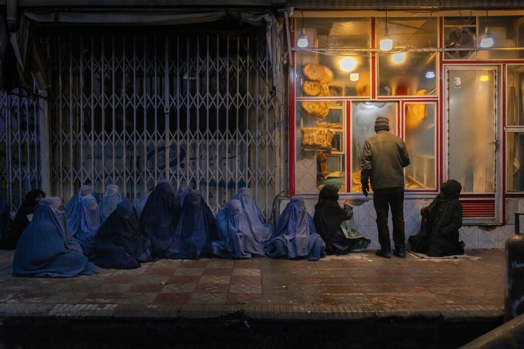 妇女和儿童在阿富汗首都喀布尔中部的一家面包店外乞讨面包（图片来源：World Press Photo）