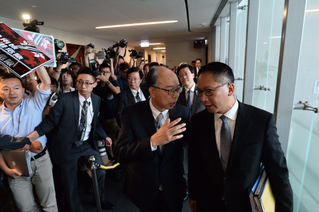 泛民持標語追着運房局局長陳帆(左)、袁國強(右)及李家超(後中)。