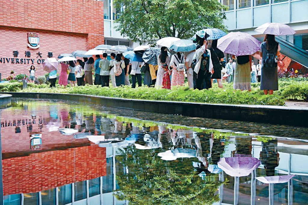 不少遊客昨在港大百周年校園內冒雨排隊，並在紅磚牆前拍照留念。