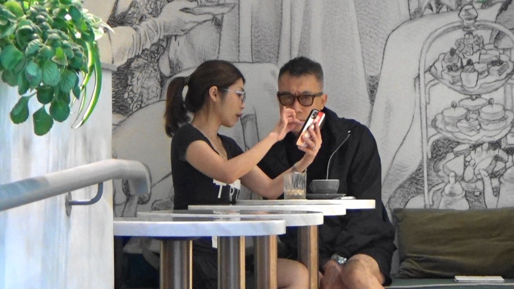 該女友人遞上電話給練海棠看,而她亦一邊講解。