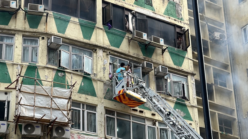 有住客在窗边呼救，由消防员升云梯救下。