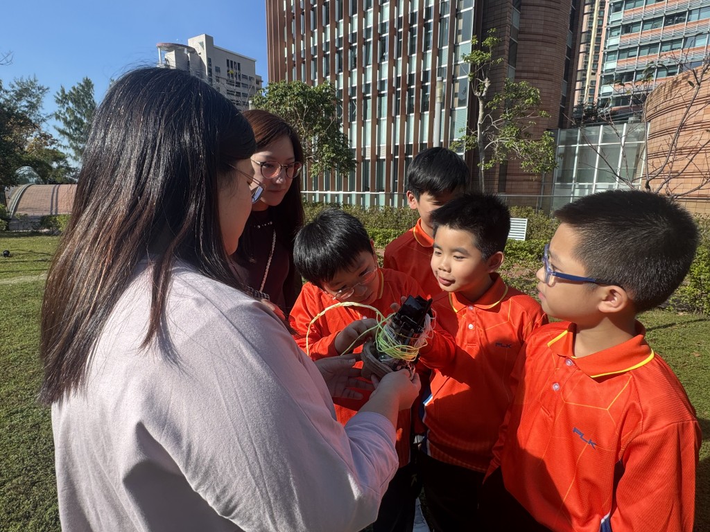 在最终放飞前，老师和香港大学的支援人员指导学生将人造卫星安装至无人机上，准备进行高空实测。（图片来源：《亲子王》）