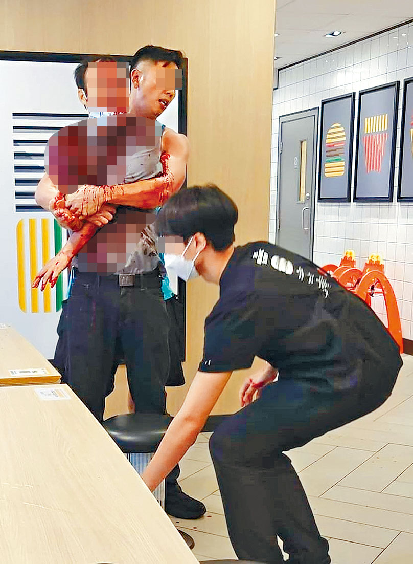 案发后受伤经理上半身制服几乎全被「染红」，一名男子从后紧抱着他，似欲让其冷静下来。