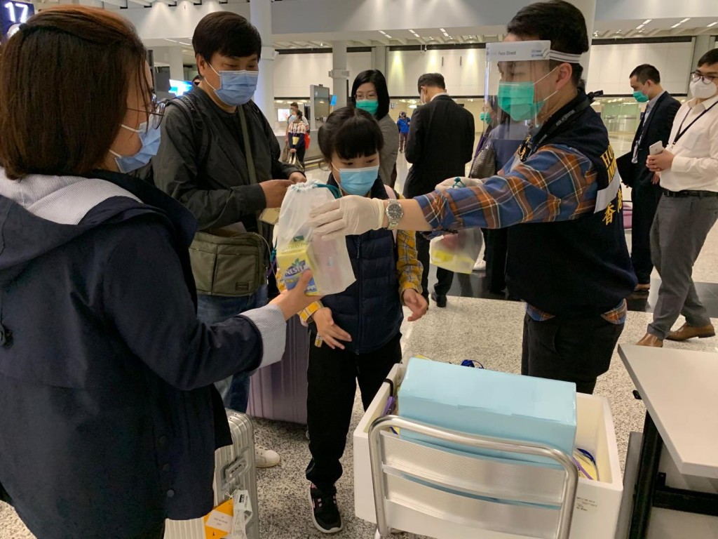 港人到達香港機場後，入境處職員為他們派發由航空公司提供的食物包。讀者提供