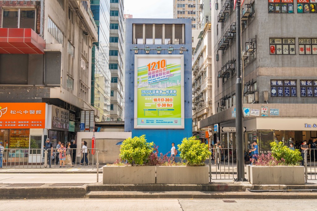 政制及内地事务局近日在全港各交通要道及建筑物外墙挂起巨型海报，宣传区议会选举。