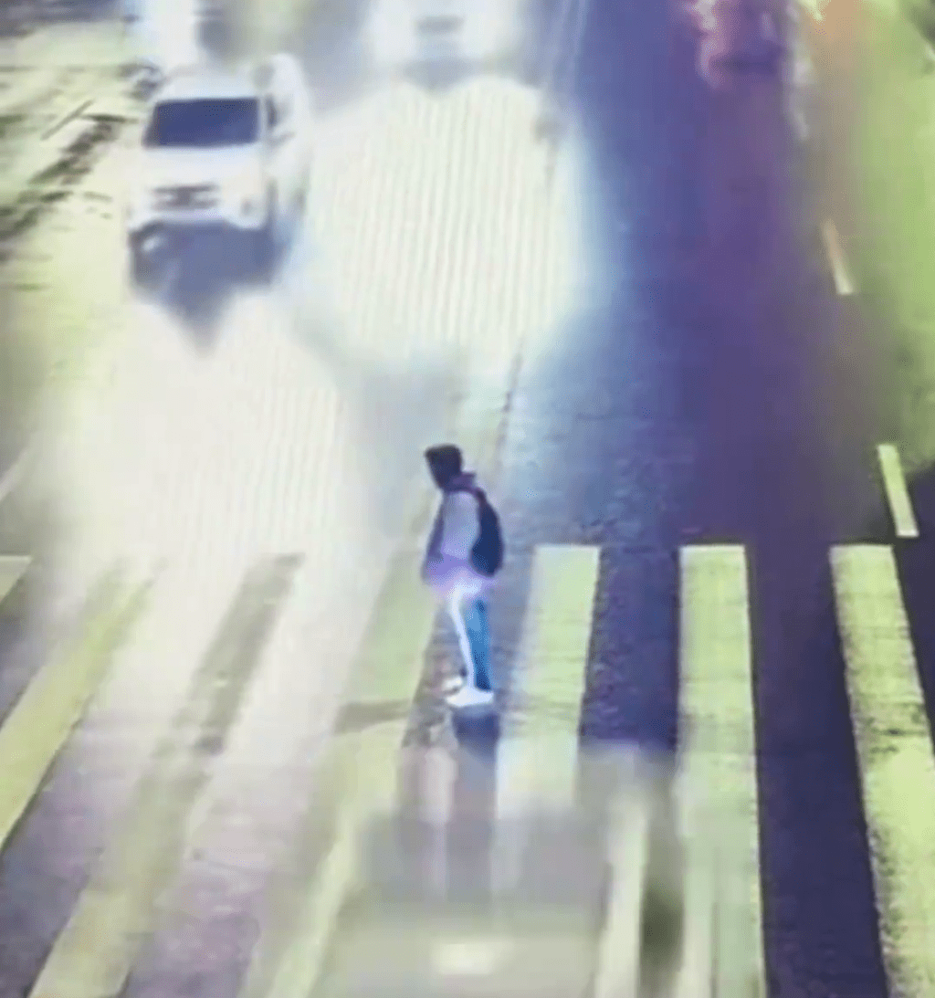 一辆车从少年左边高速驶至。