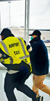 ■身穿黃色機場的士背心的洋漢突然拉着季炳雄(右),加快步伐圖擺脫記者。