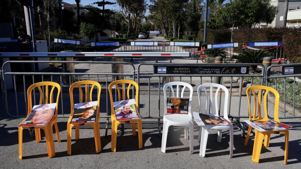 人质家属及支持者在空凳上放人质肖像海报以示抗议。 路透社