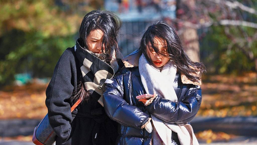 北京降溫，市民昨天在街頭出行。 中新社圖片