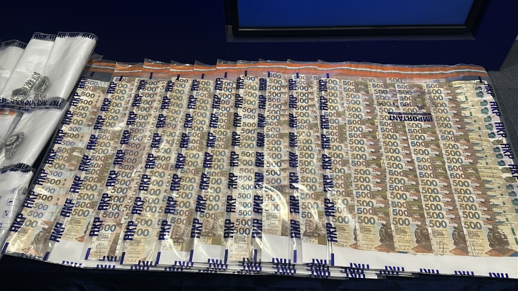 警方展示涉案財物，包括名錶、現金及名酒。