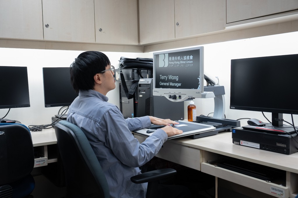 鄭浩欣（香港失明人協進會 高級數碼無障礙專員）示範使用幫助視障人士閱讀的桌面放大機。