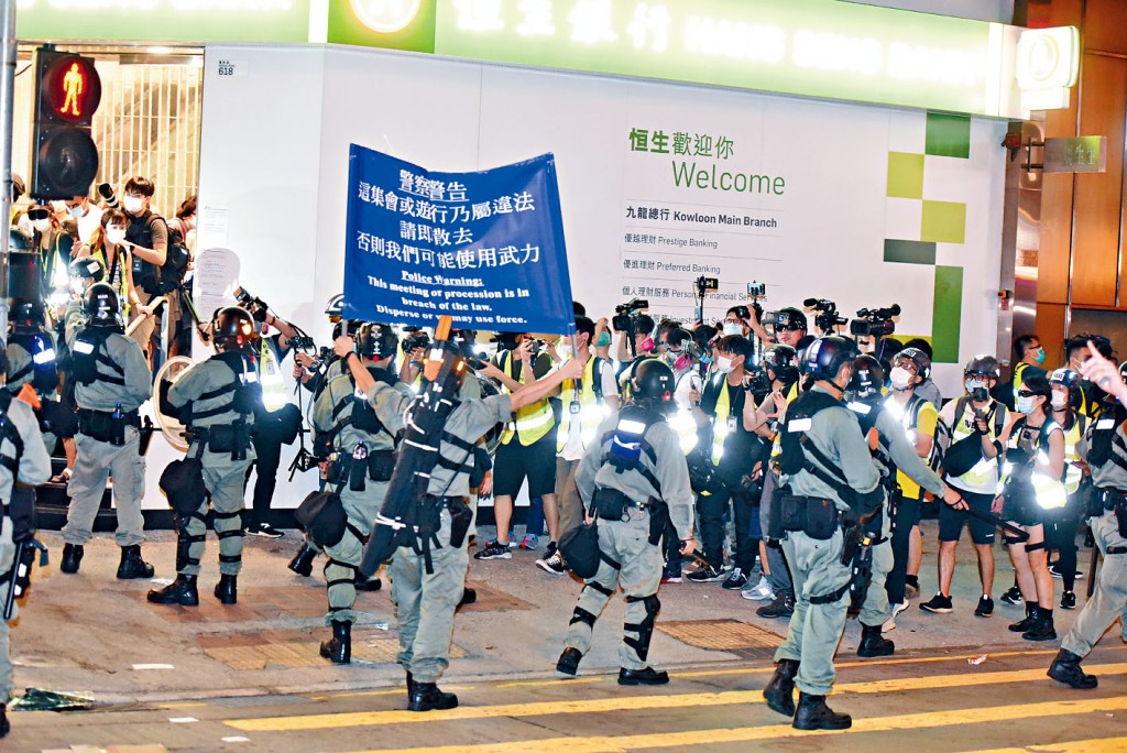 防暴警举旗警告，劝令人群离开。