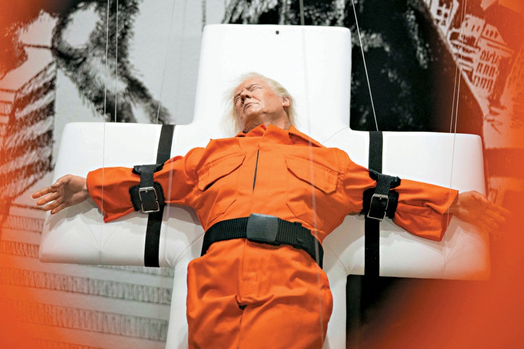 英國藝術家Mason Storm創作「聖人還是罪人」雕塑，展現特朗普身穿囚服被綁在十字架上，本周在瑞士展出。 