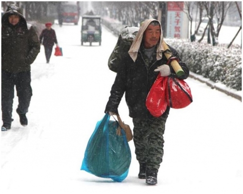 用毛巾搭在了頭上，肩扛手提生活用品，就走上回家的路。