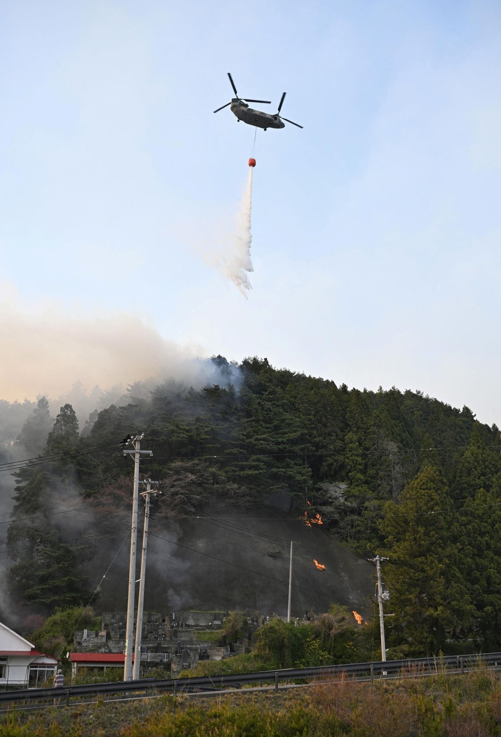 直升機在空中撒水救火。路透社
