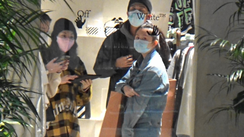 朋友拎出手機向店員詢問有冇貨，在旁的沈日發現記者在場。