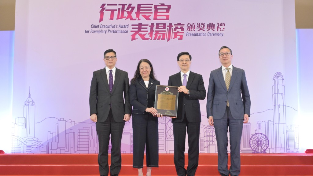 李家超(右二)向專責小組代表兼時任保安局副秘書長廖李可期(左二)頒授獎狀。旁為律政司司長林定國(右一)和保安局局長鄧炳強(左一)。政府新聞處