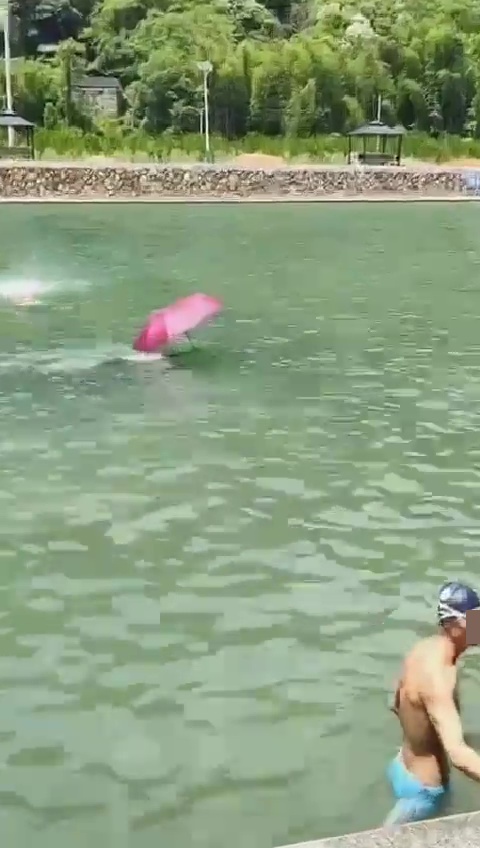 看真一点，原来是有泳客撑伞畅泳。网上截图