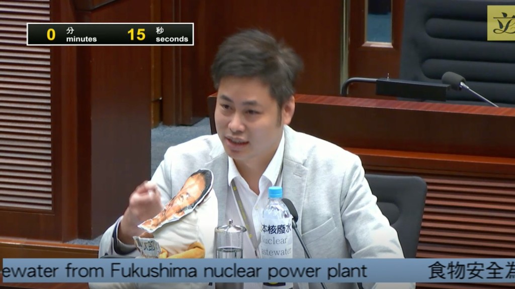 渔农界的何俊贤在议员桌上展示前日本首相麻生太郎的「公仔」，斥其核废水「饮得」言论有问题。 立法会直播截图