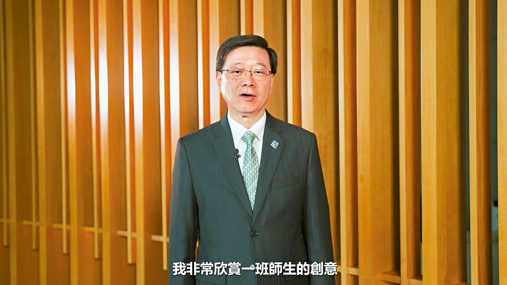 李家超表示，襟章和領呔圖案一脈相承，寓意香港積極發揮「背靠祖國、聯通世界」獨特優勢。