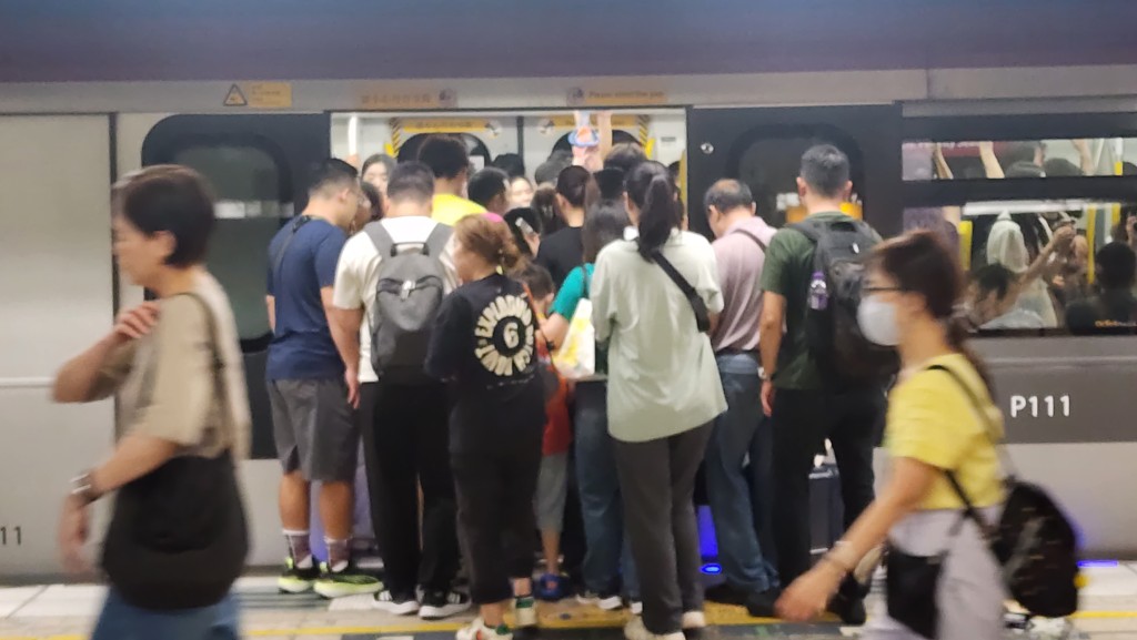 列车到站后，大批市民挤入车厢。黄文威摄