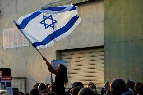 塞浦路斯一所猶太教堂外舉行聲援以色列集會上，一名女孩揮舞著以色列國旗。美聯社