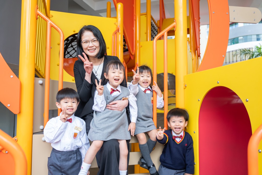 幼稚園部校長張展鈴博士在遊樂場與K1學生嬉戲，實踐「校本自由遊戲」理念。（圖片來源：《親子王》）