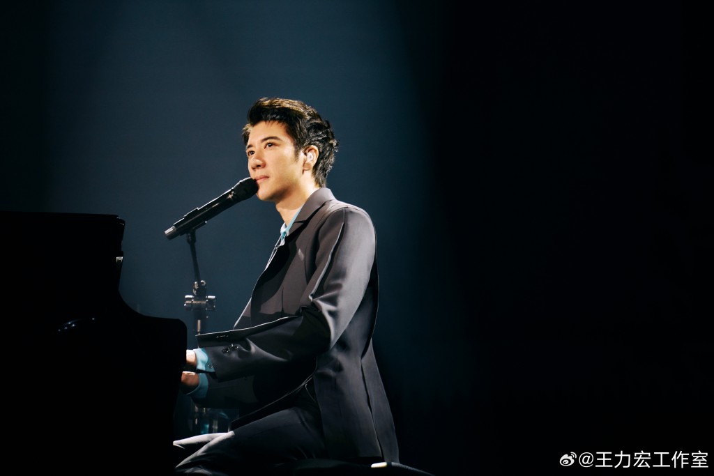 王力宏在演唱会上表演弹钢琴。