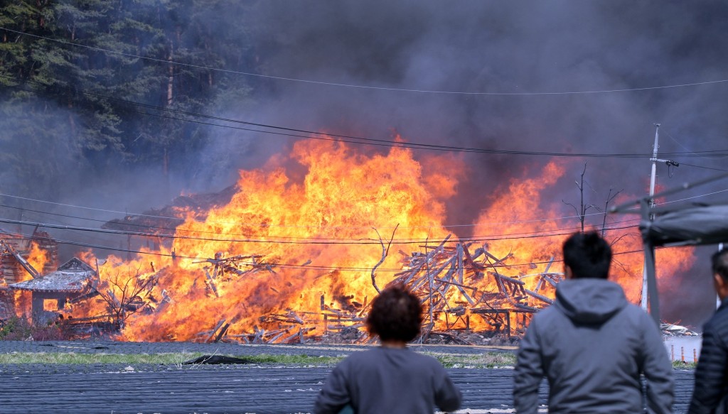 江陵市山林大火，居民無奈看着建築物燒剩支架倒塌。 路透社