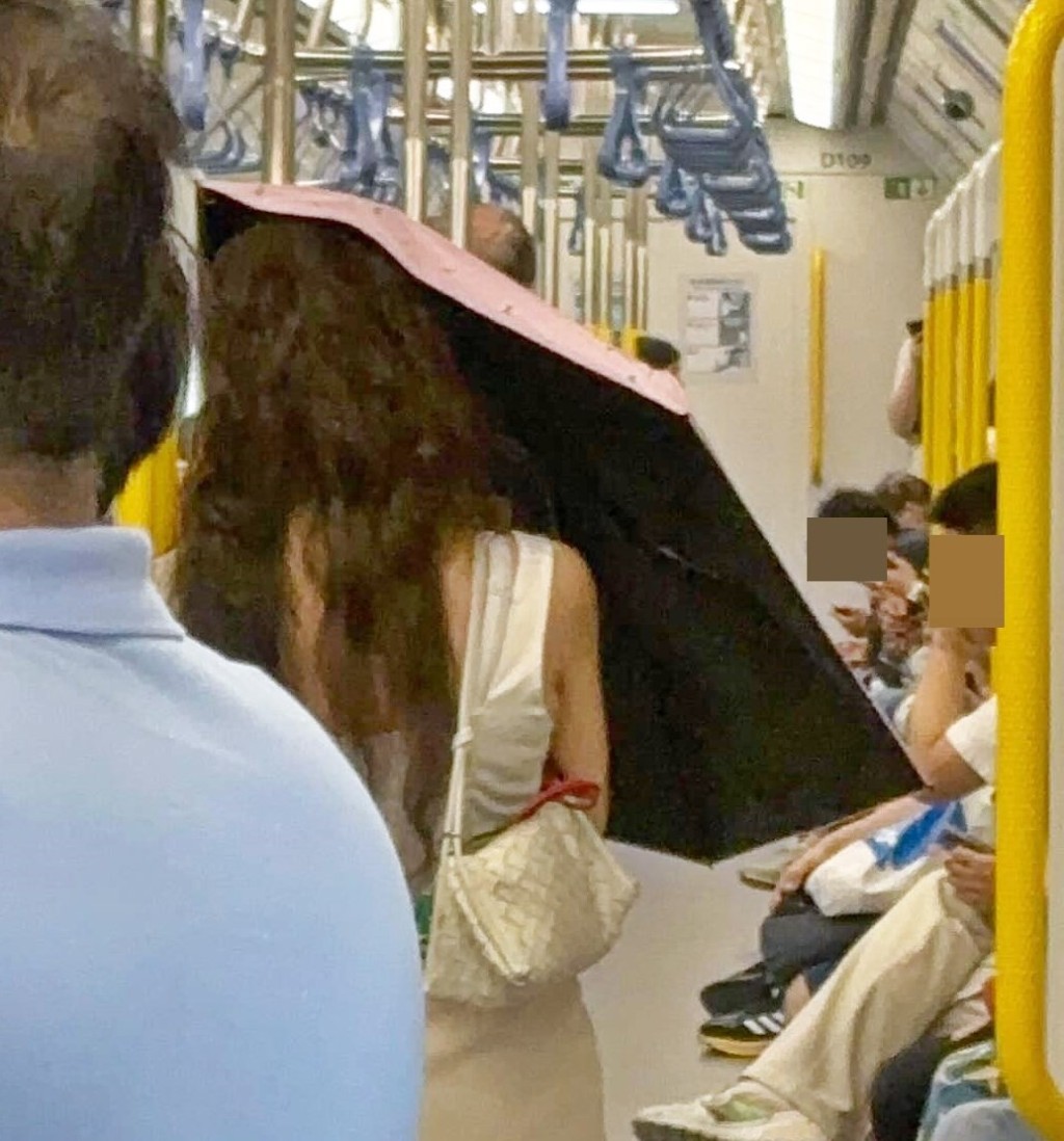 片中見到一名穿白色短裙的長髮女子,在車廂內撐起雨傘。Threads截圖 片中見到一名穿白色短裙的長髮女子,在車廂內撐起雨傘。Threads截圖