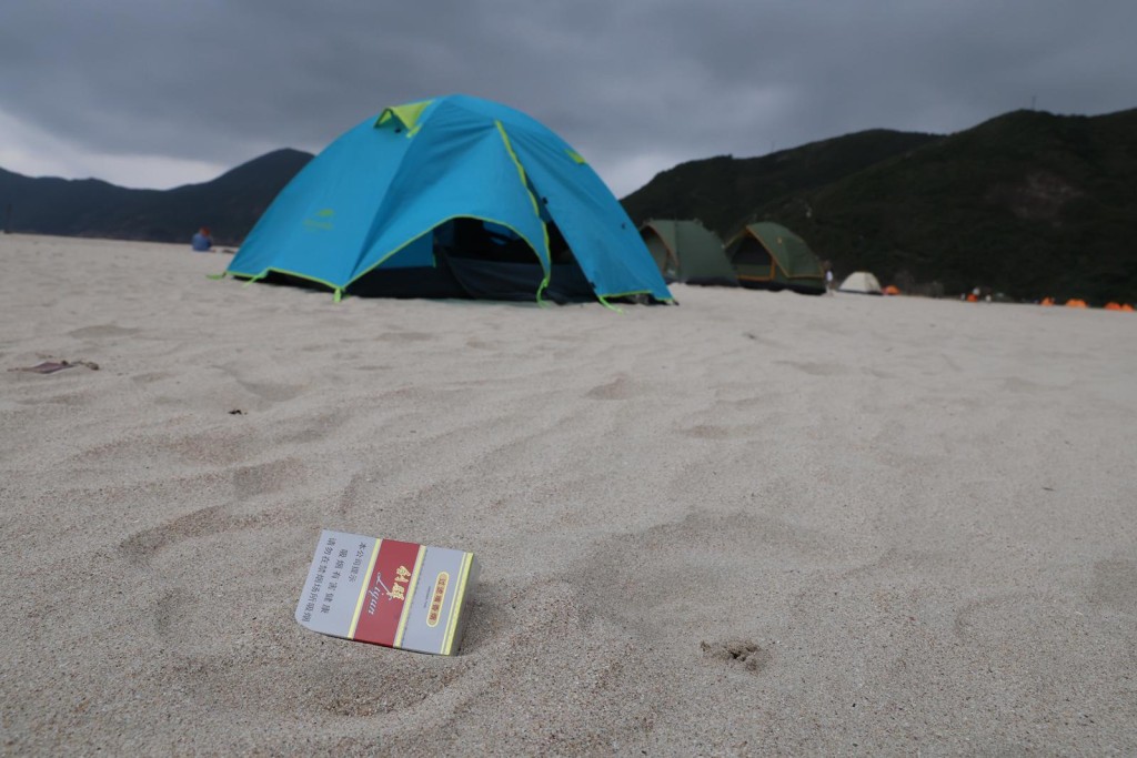 沙灘上遺下印有簡體字的空煙盒。 沙灘上遺下印有簡體字的空煙盒。