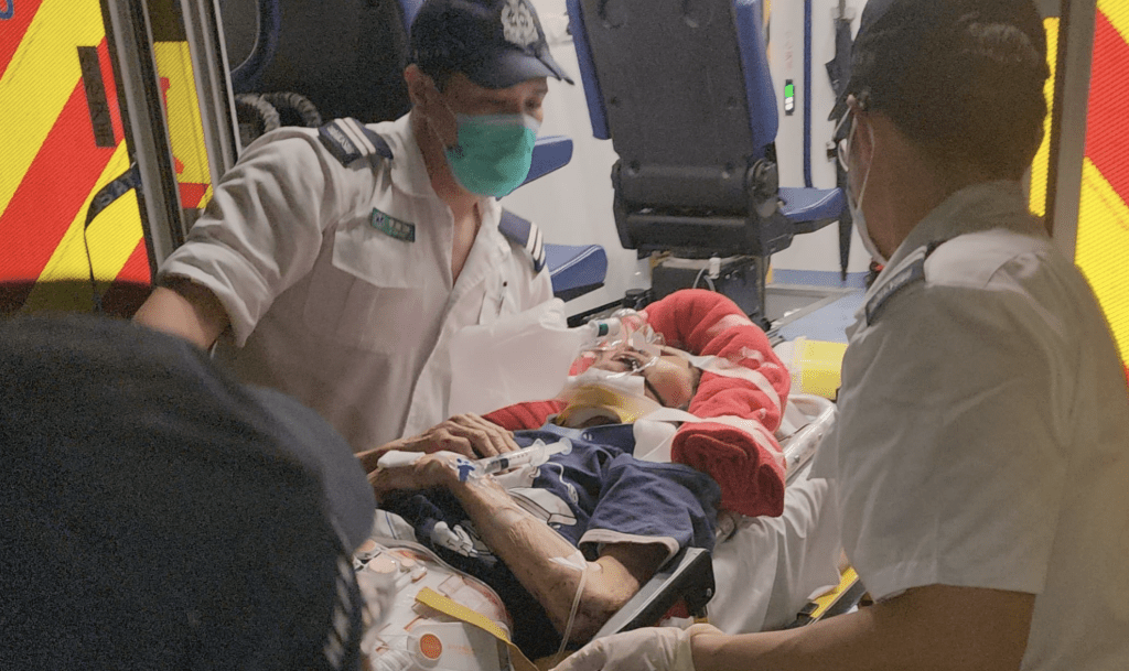 救护员将伤者抬上救护车送院。黄文威摄