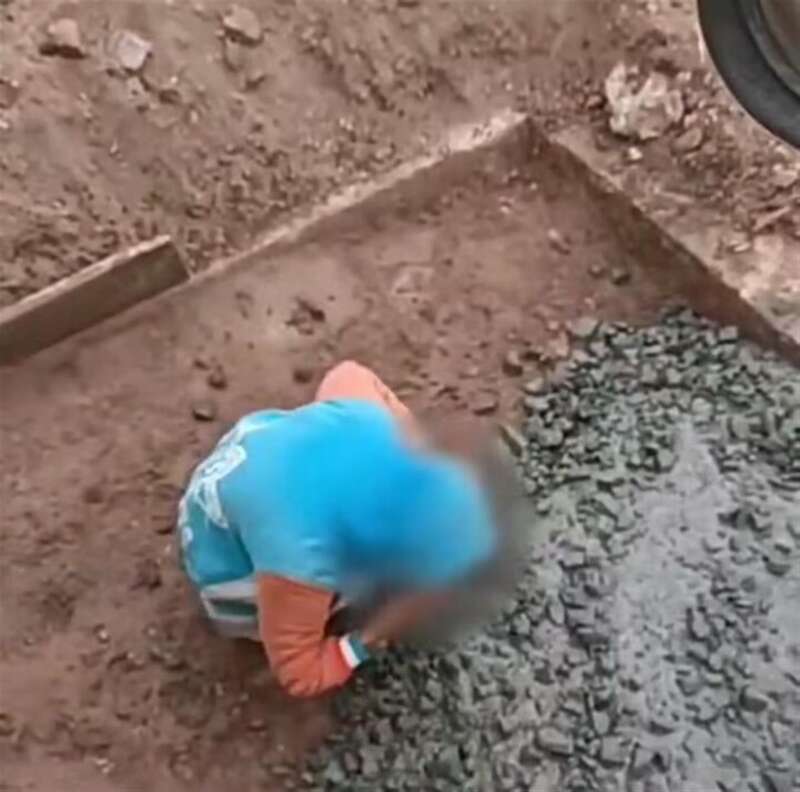 男孩在雨天蹲在地上捡拾混凝土放进嘴里。