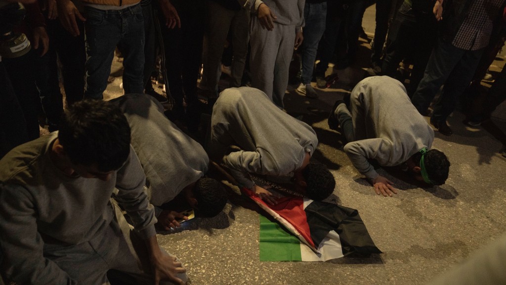 几名巴勒斯坦人返抵西岸贝图尼亚（Beitunia）后跪地祈祷。 美联社
