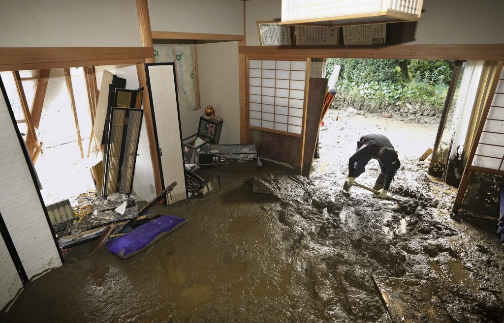 九州暴雨导致多条河流泛滥，引发泥石流，道路封闭。一名男子正在清理被暴雨损坏的房屋。AP