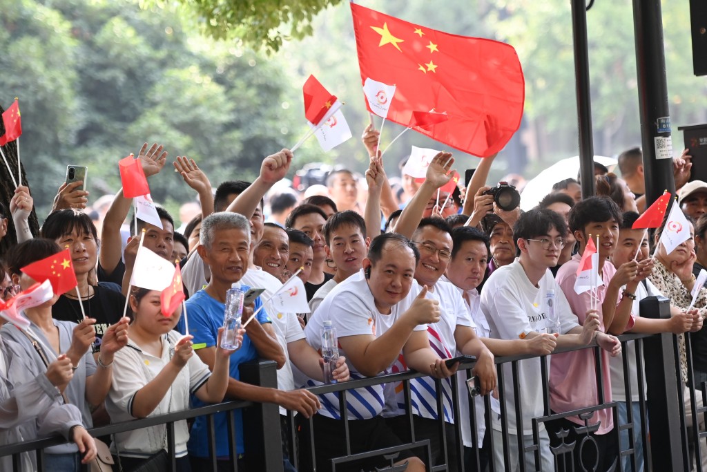 杭州亚运会火炬传递启动，人们在路边等待火炬传递。新华社