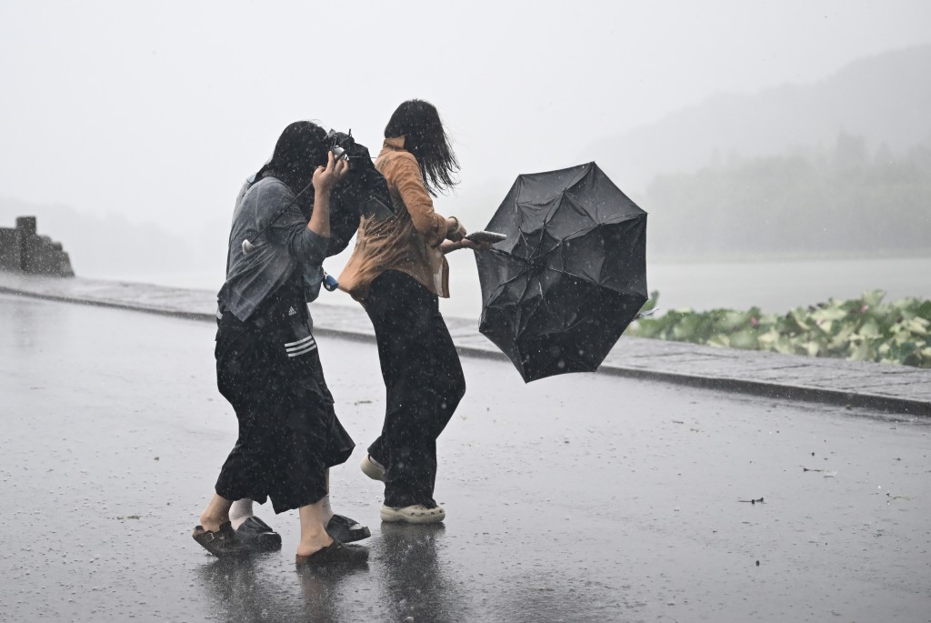 “白海豚”吹袭期间,西湖断桥游人雨伞被吹翻。中新社 “白海豚”吹袭期间,西湖断桥游人雨伞被吹翻。中新社